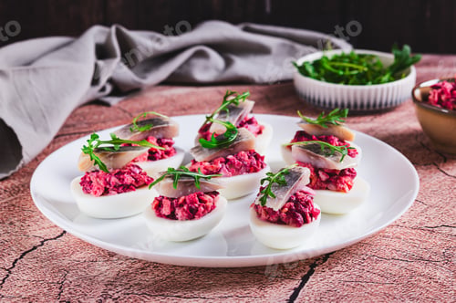 Preview: Egg halves stuffed with herring under a fur coat on a plate on the table