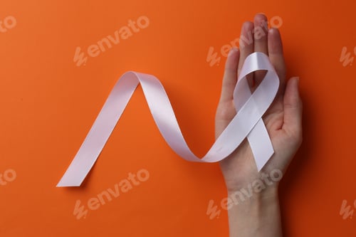 Preview: Woman holding white awareness ribbon on orange background, top view