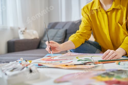 Preview: A woman in yellow shirt painting and looking involved
