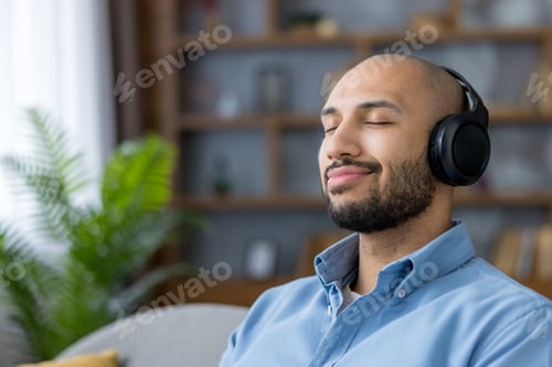 Preview: Man enjoying music with wireless headphones relaxing at home