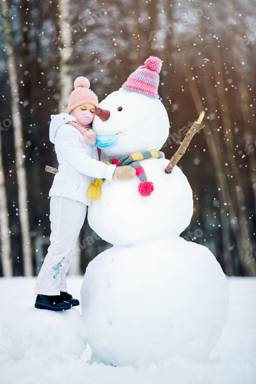 Preview: A child girl wearing a mask on a snowman ,playing with a snowman on a winter walk in nature