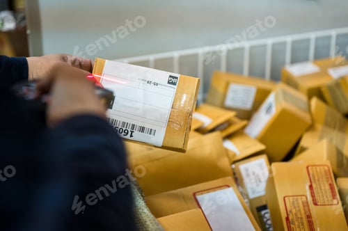 Preview: Delivery man using laser scanner scanning parcel cardboard box in distribution center