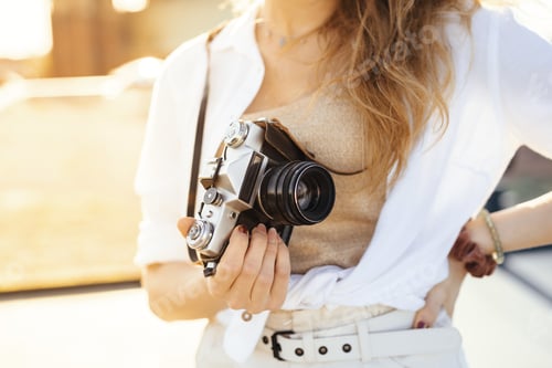 Preview: Close up shot of a fashionably dressed blonde woman posing with a camera