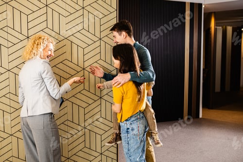 Preview: Saleswoman showing a young couple with a child the panels for decorating the interior of the home.