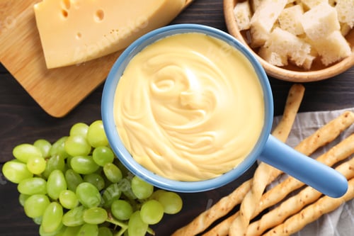Preview: Pot with tasty cheese fondue and products on table, flat lay