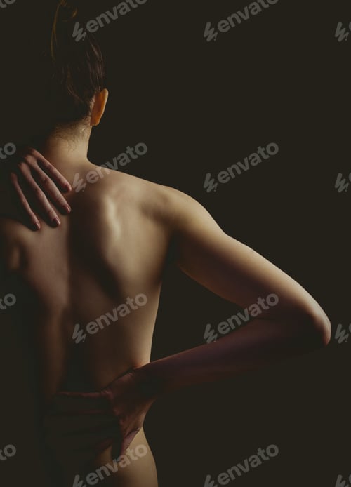 Preview: Nude woman with a back injury on black background