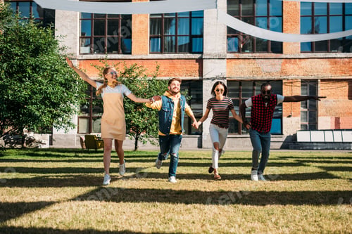Preview: multicultural young friends holding hands while having fun together on summer day