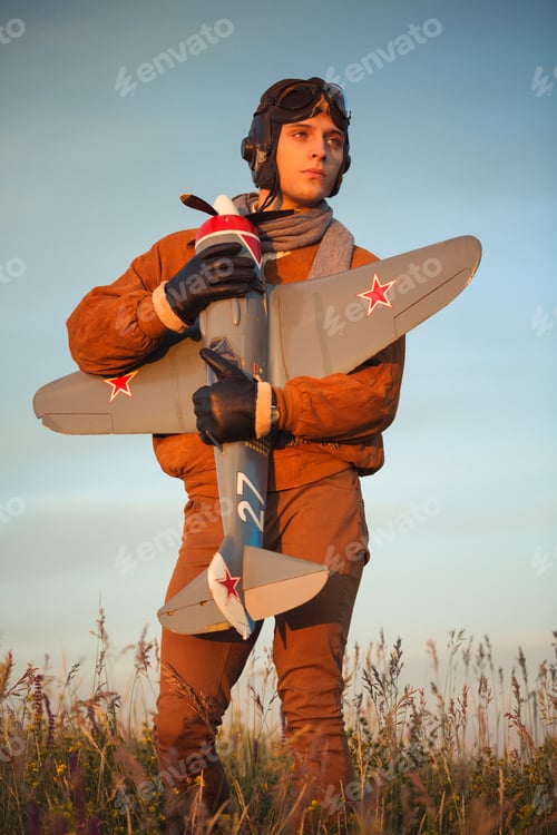 Preview: Guy in vintage clothes pilot with an airplane model outdoors