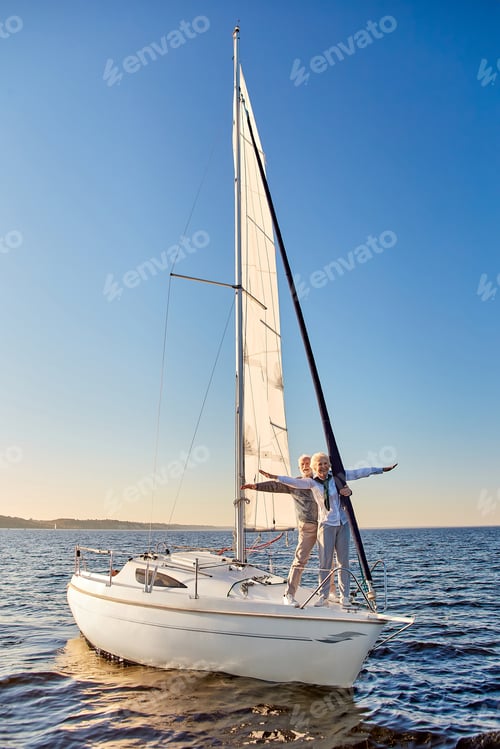 Preview: Happy senior couple stretching hands out against the sky, looking at the horizon and enjoying