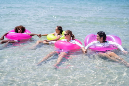 Preview: Teenage girl friendship enjoy laughing play on sea swimming with water inflation toy on blue sky day