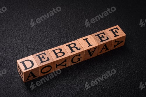 Preview: The inscription debrief in wooden cubes on a dark concrete background