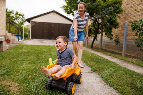 Preview: Mother having fun pushing child in toy truck