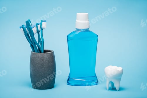 Preview: Toothbrushes, mouthwash and white model of tooth on blue background