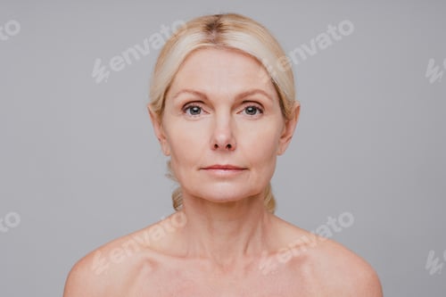 Preview: Close up portrait of middle-aged beautiful woman showing her beauty isolated over grey background