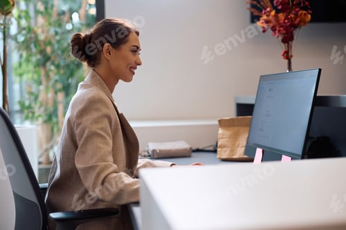Preview: Happy female manager working on a computer at corporate office.