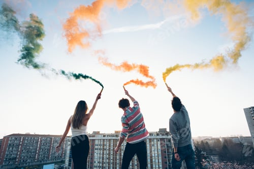 Preview: Group of friends on roof, holding colourful smoke flares, rear view