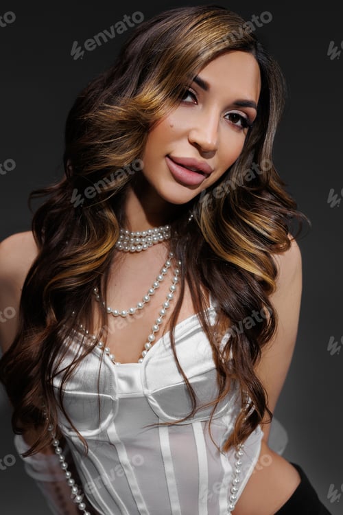 Preview: Portrait of a woman in a white blouse and with pearl beads in the spotlight in the studio.