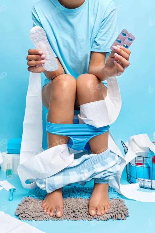 Preview: Cropped shot of faceless woman has painful menses holds painkillers and sanitary napkin poses on toi