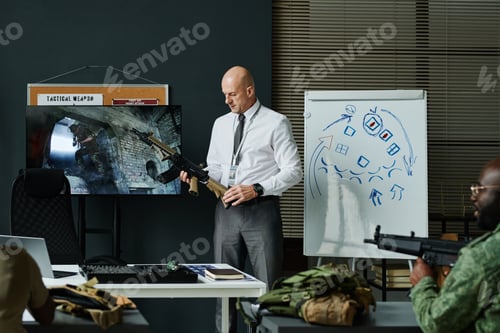 Preview: Mature male teacher or officer making presentation of machine gun