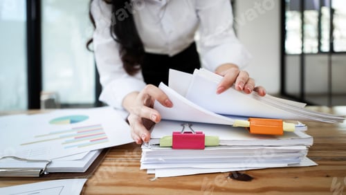 Preview: Businesswoman hands working in Stacks of paper files for searching and checking unfinished document
