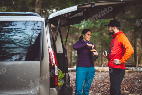 Preview: A man and a woman preparing drinks from a thermos in the back of a car, surrounded by nature. The ma