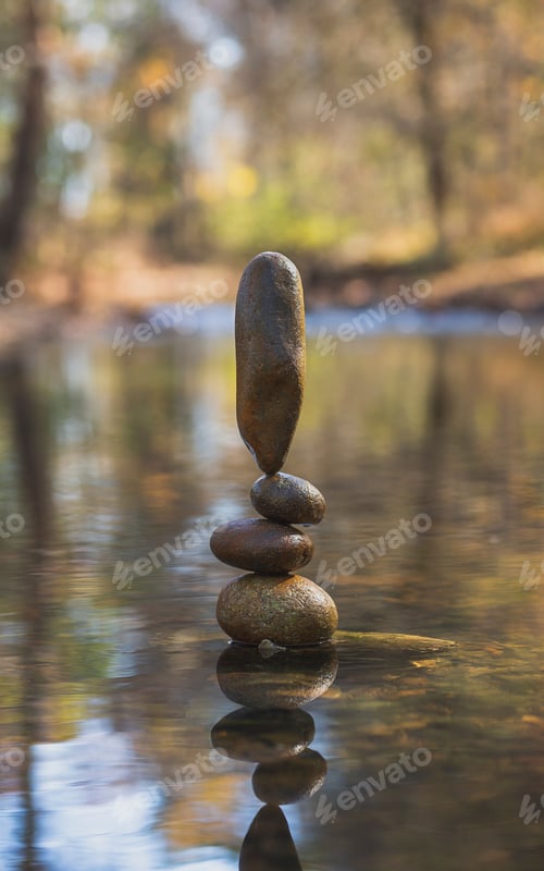 Preview: Vertical shot of rocks balanced on each other at the lake in the forest