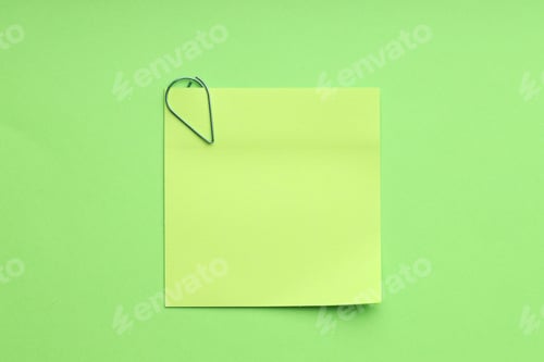 Preview: Blank paper note attached with clip on green background, top view