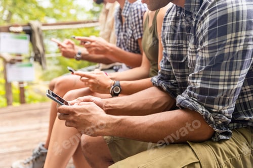 Preview: Italy, Massa, hikers in the Alpi Apuane mountains looking at their smartphones and sitting on a benc