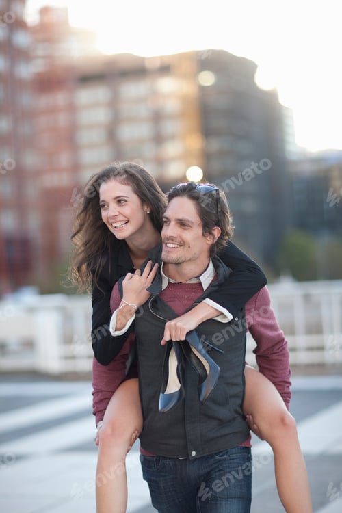 Preview: Mid adult man giving girlfriend piggyback in street