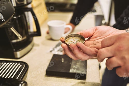 Preview: Closeup of adult male hand holding a dispersion screen that needs cleaning from an espresso machine