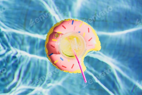 Preview: Tasty cocktail with ice and fresh limon on inflatable donut toy at swimming pool.