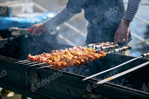 Preview: Cooking pork barbecue with skewers cubes of meat on BBQ grill, traditional Central Asia dish