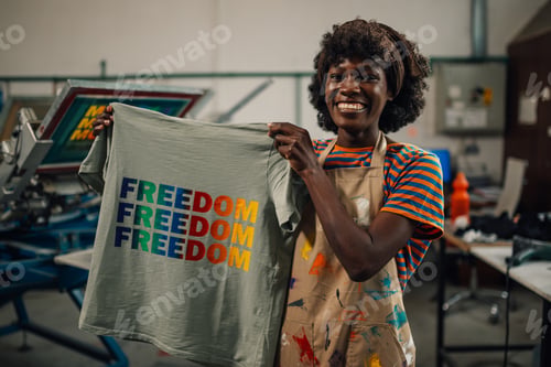 Preview: Diverse smiling graphic worker showing textile product at the camera.