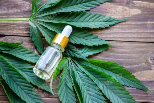 Preview: cannabis leaves on wood background with bottles, cannabis oil.