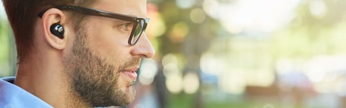 Preview: Side view of a young handsome businessman listening to music with wireless earphones