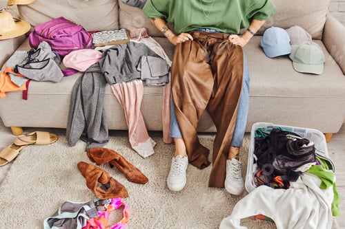 Preview: partial view of tattooed and stylish woman sitting on couch with leather pants during clothing