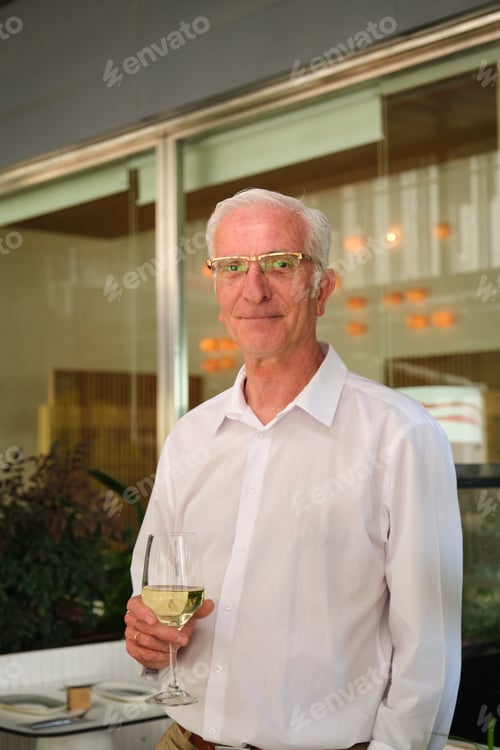 Preview: Elegant mature man drinking white wine at a restaurant's happy hour