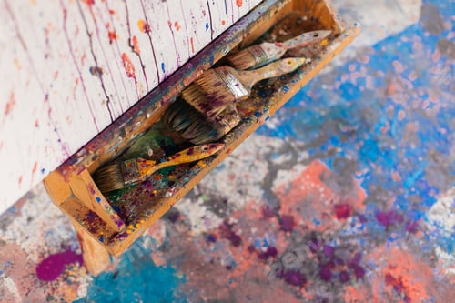 Preview: Close up photo of paintbrushes and picture on canvas with paints