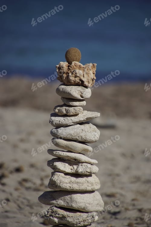 Preview: Scenic view of pebbles on a sandy beach with seashore in background
