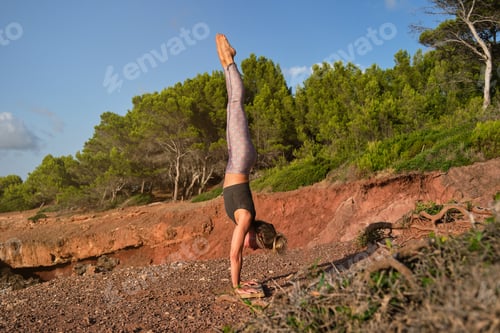 Preview: Woman in tights practicing handstand yoga in the middle of the f