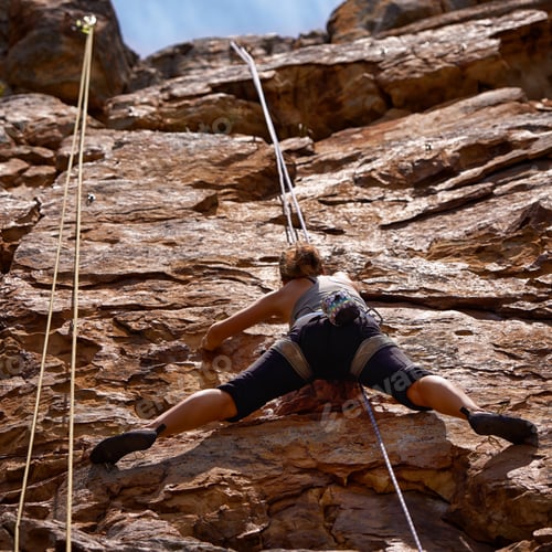 Preview: Shes challenging herself on this climb. Shot of a young female climber traversing a rock face.