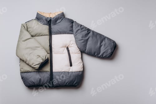 Preview: Fashion baby colorblock puffer jacket on grey background. Newborn beige clothes outfit.