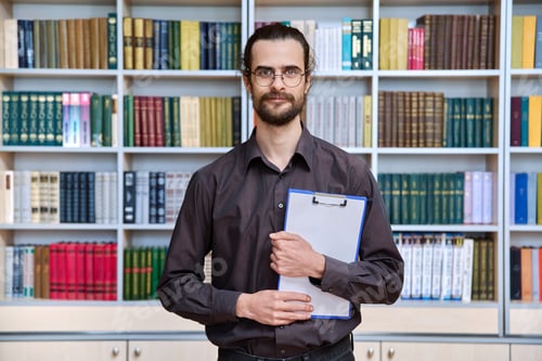 Preview: Portrait young male with clipboard in library