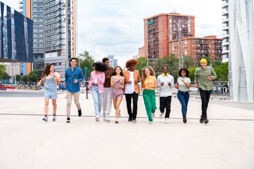 Preview: Happy playful multiethnic group of young friends bonding outdoors