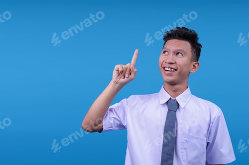 Preview: Positive Indonesian High School Student Guy Showing Aha Moment Gesture With Pointing Up