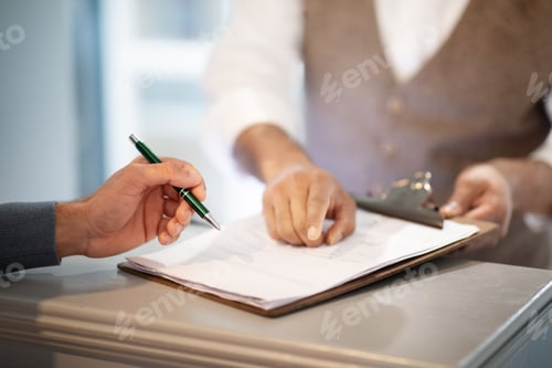 Preview: Closeup Of Man Signing Papers Checking In At Hotel Reception