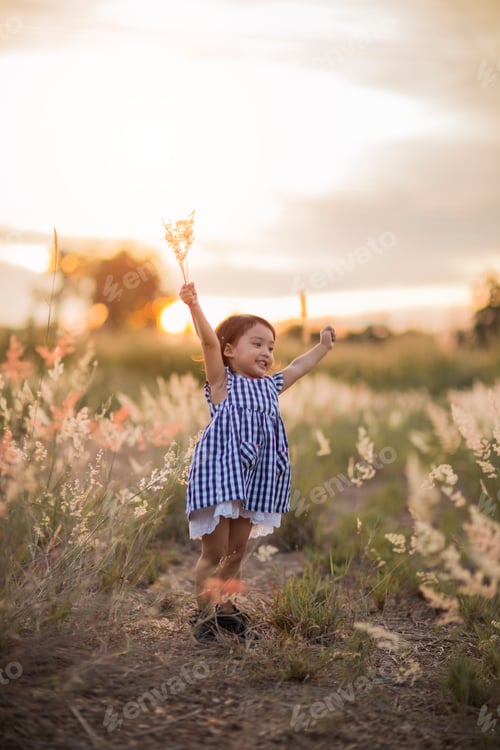 Preview: Happy cute kid in a field playing with natural spikes at summer sunset. Soft colors edition.