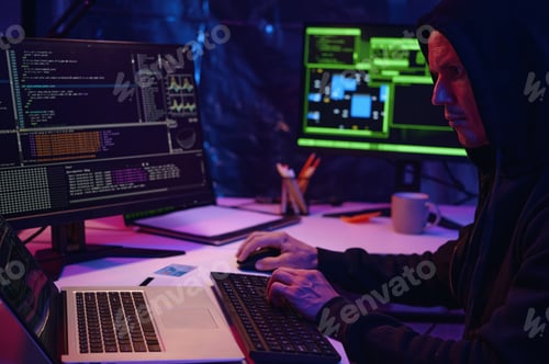 Preview: Hooded Man Works on Computer Code at Night