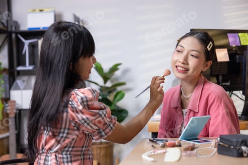 Preview: Woman applying makeup on friend indoors