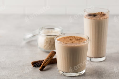 Preview: Glasses with a cold drink based on Horchata rice, cinnamon sticks and a jar of rice.